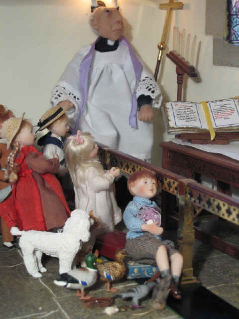 The vicar continues to give the children a talk about the different Christmas colours.  Robert Alexander is bored and lounging on the altar rail clutching his cabbage!